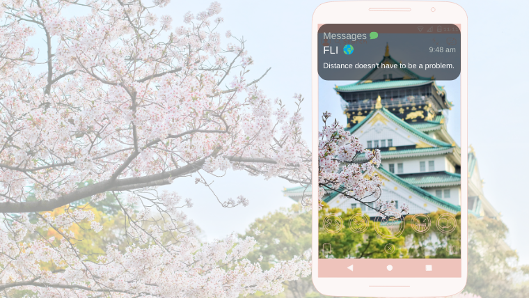 Cell phone text 'Distance does not have to be a problem' in front of picture of Japanese cherry blossoms