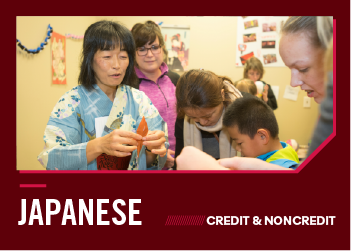 A woman in a kimono teaches students and children how to fold origami.