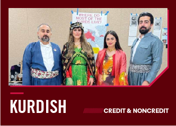 Four people in traditional Kurdish attire stand in front of a poster.